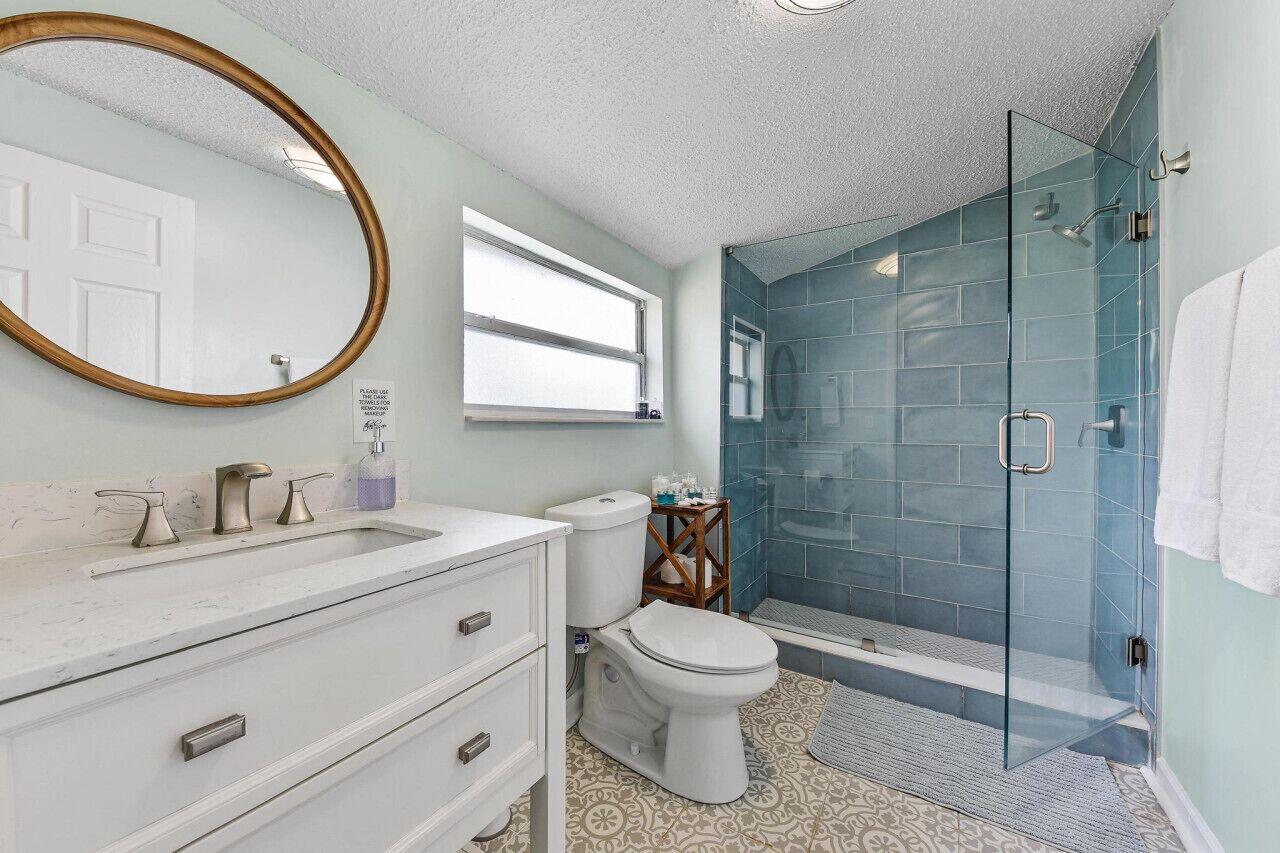 A bathroom with a white vanity, a glass shower enclosure, and a toilet.
