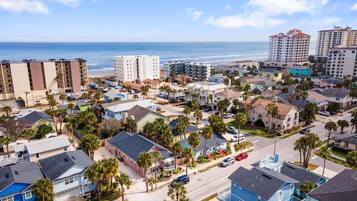 A coastal residential area with a mix of single-family homes and multi-story buildings, featuring a beach view.