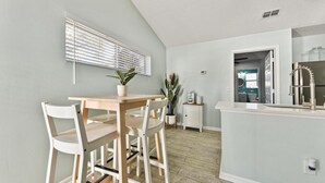 A modern kitchen with a white countertop, a built-in oven, and a stainless steel refrigerator. - Pink Dolphin 3| Beachside Cottage| Walk Everywhere (Jacksonville Beach)