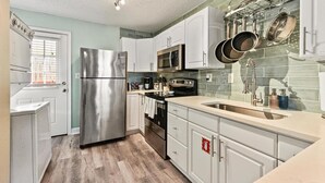 Una cocina moderna con armarios blancos, electrodomésticos de acero inoxidable y un salpicadero de azulejos.