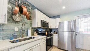 Una cocina moderna con armarios blancos, electrodomésticos de acero inoxidable y un salpicadero de azulejos azules.
