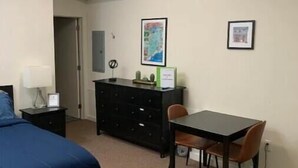 A bedroom with a bed, a dresser, a desk with two chairs, and a map on the wall. - Studio in the heart of Fishtown (Philadelphia)