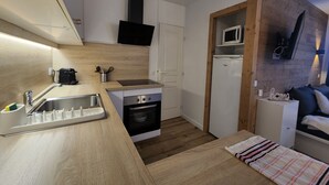 Eine kleine Küche mit Spüle, Herd, Backofen, Mikrowelle und einer Holzwand.