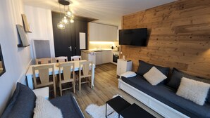 Ein modernes Wohnzimmer mit einer Couch, einem Couchtisch und einem Essbereich mit Stühlen und einem Tisch.