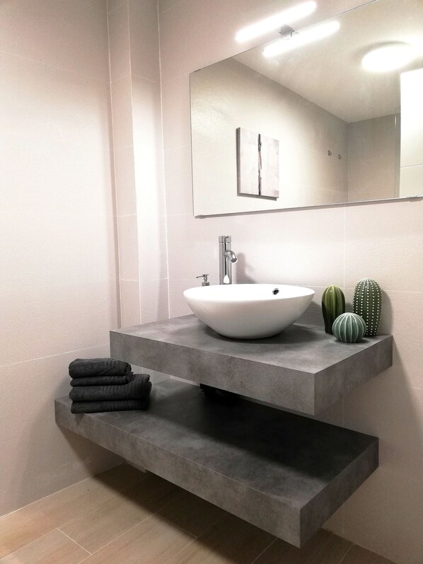 Modern bathroom with a large vessel sink, single faucet, and ample storage.