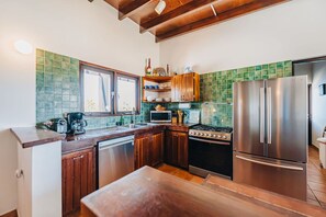 A modern kitchen with wooden cabinets, a stainless steel refrigerator, a stove, and a dishwasher.