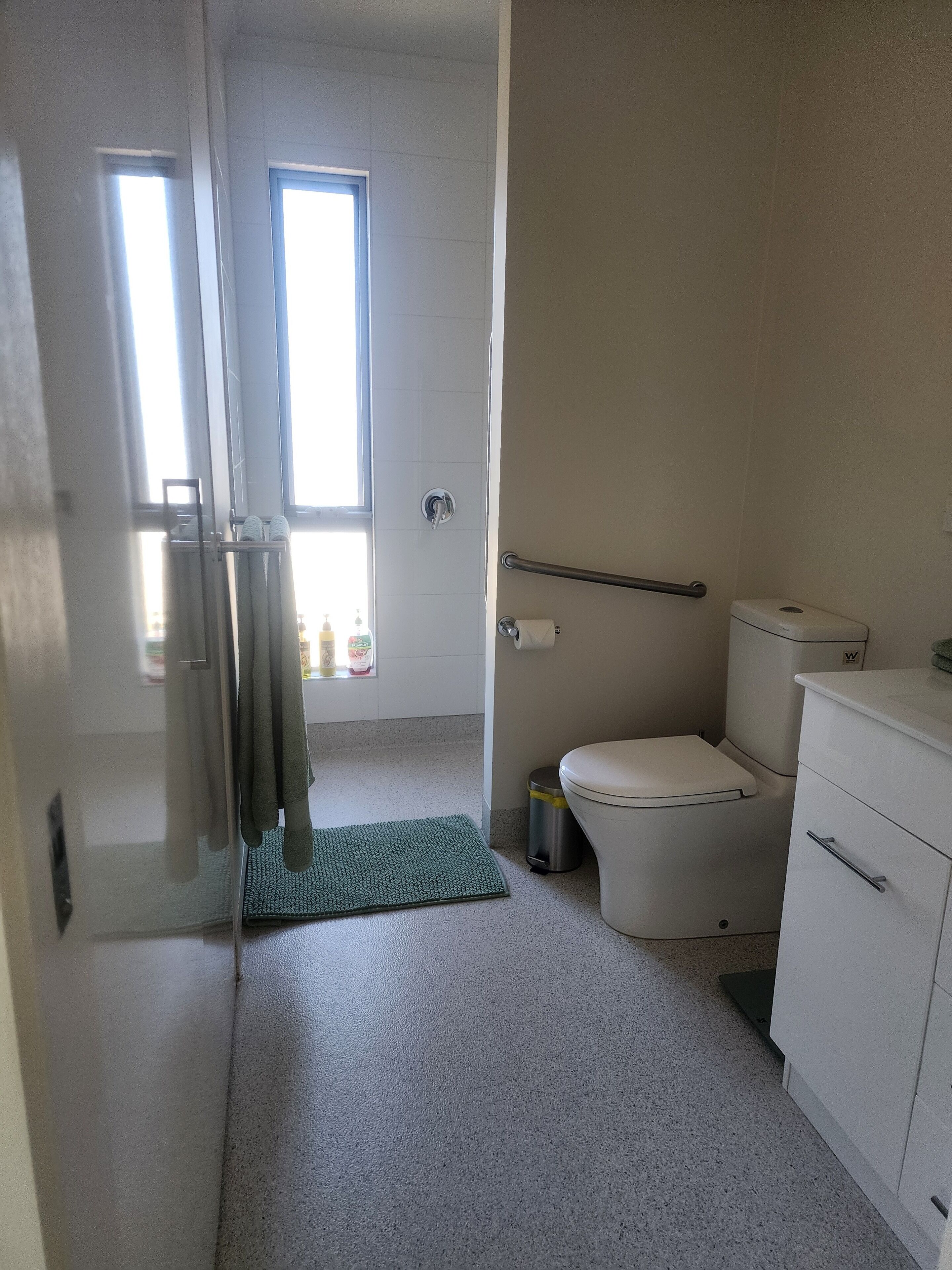 A small, clean bathroom with a toilet, a trash can, and a towel rack.