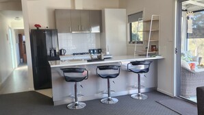 A modern kitchen with a central island, bar stools, and a dining area with a table and chairs. - Private Two Bedroom unit located on 63 acres Stunning views. 
Beautiful Sunroom. (Mountain River)