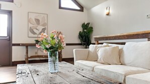 Ein Wohnzimmer mit einem Holztisch, einem weißen Sofa und einer Blumenvase.