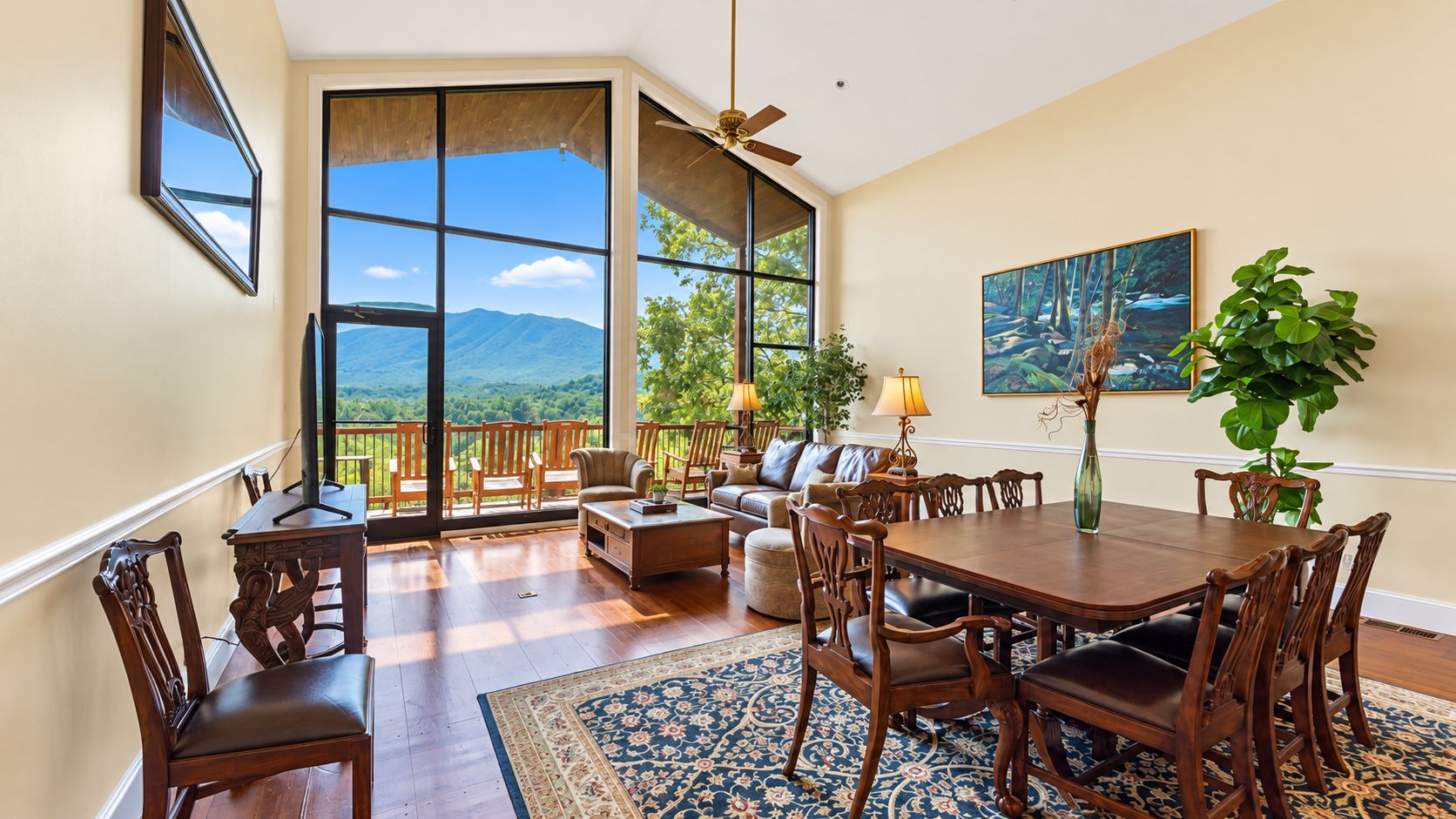 A spacious living area with a large window, a dining table, and a sofa.