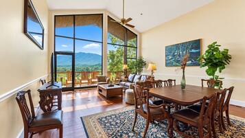 A spacious living area with a large window, a dining table, and a sofa.