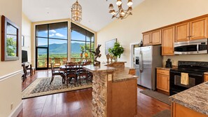 A spacious kitchen with a large island, stainless steel appliances, and a view of the mountains through the sliding glass doors.