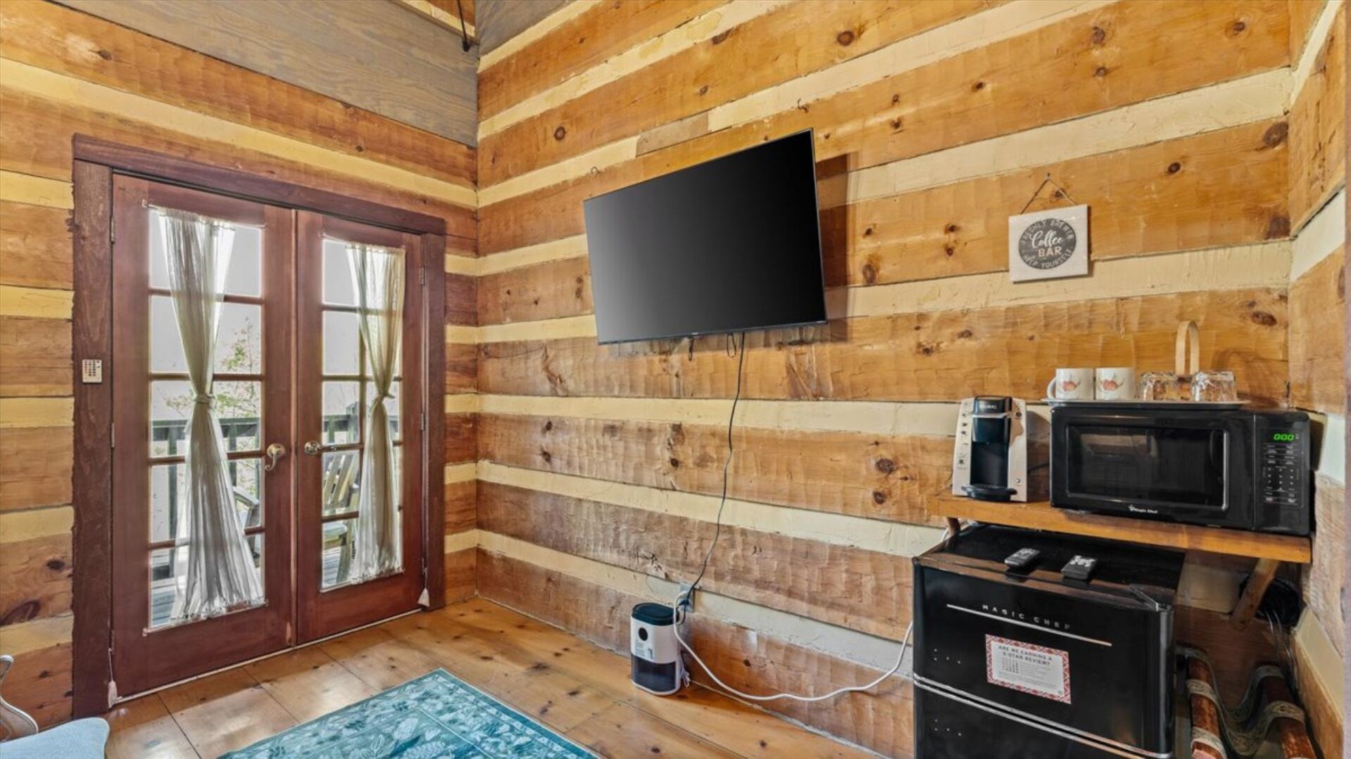 Een houten cabinemeubilering met een aan de muur bevestigde televisie, een koffiezetapparaat, een magnetron en een koelkast.