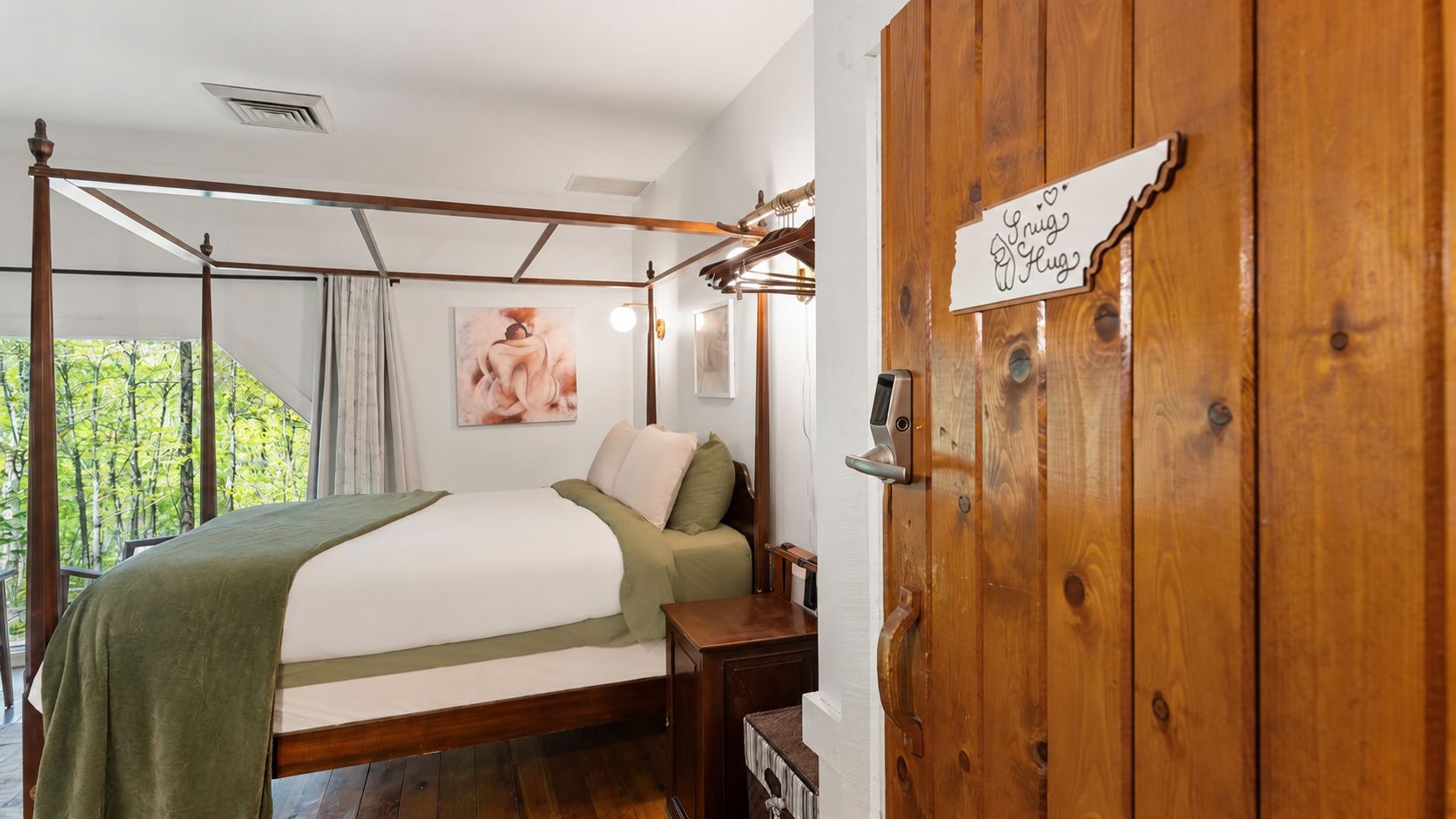 A bedroom with a four-poster bed, a wooden door with a sign, and a view of greenery outside.