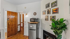 A compact kitchen with a refrigerator, microwave, and coffee maker on a wooden countertop. A sign on the door reads "Coffee Bar." - Tree-View Room | 4-Poster Bed | Walk-In Shower + Coffee (Townsend)