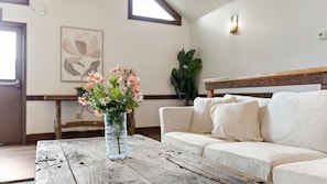 Una sala de estar con una mesa de centro de madera, un sofá blanco y un jarrón con flores.