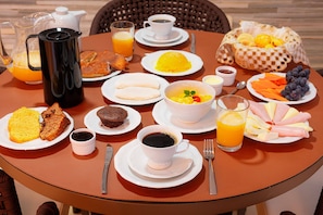 A breakfast table with various dishes including toast, eggs, fruit, and beverages. - Joia Rara Pousada (Pirenópolis)
