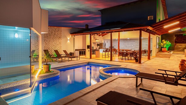 A swimming pool with lounge chairs and a covered patio area. - Joia Rara Pousada (Pirenópolis)