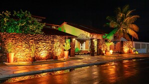 A stone-walled building with a gated entrance, potted plants, and a palm tree. - Joia Rara Pousada (Pirenópolis)
