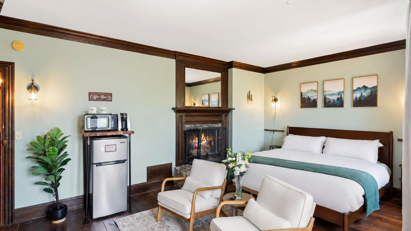 Ein Hotelzimmer mit einem Bett, einem kleinen Schreibtisch mit Mikrowelle, einem Kamin und einer Sitzecke mit Stühlen.