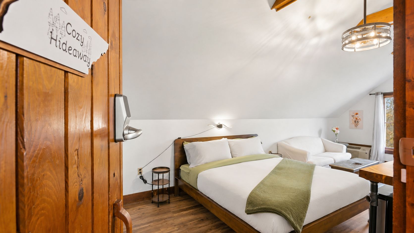A cozy hideaway bedroom with a bed, bedside table, lamp, and a small round table.