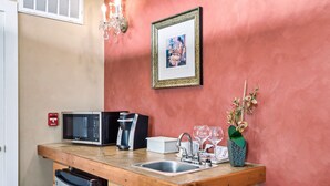 A compact kitchen with a microwave, coffee maker, sink, and a small refrigerator.