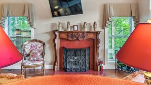 A room with a fireplace, a television mounted on the wall, and a chair with a patterned cushion.