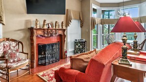 A living room with a fireplace, a television mounted on the wall, and a red chair.