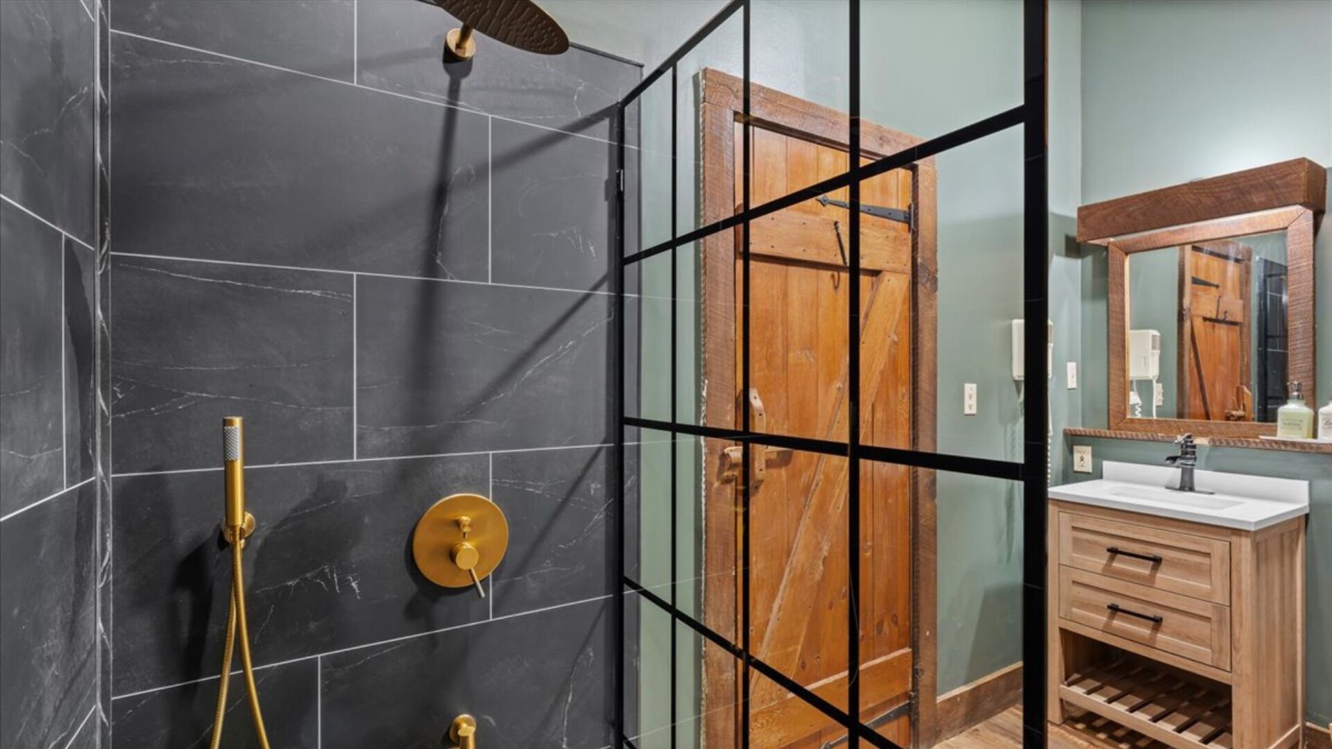 Un baño con ducha, tocador y puerta de madera.