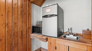 Een kleine keuken met een ingebouwde koelkast, een magnetron en een spoelbak.