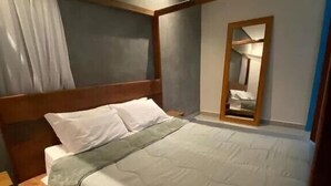 Un lit à baldaquin avec du linge de lit blanc, une tête de lit en bois et une table de chevet.