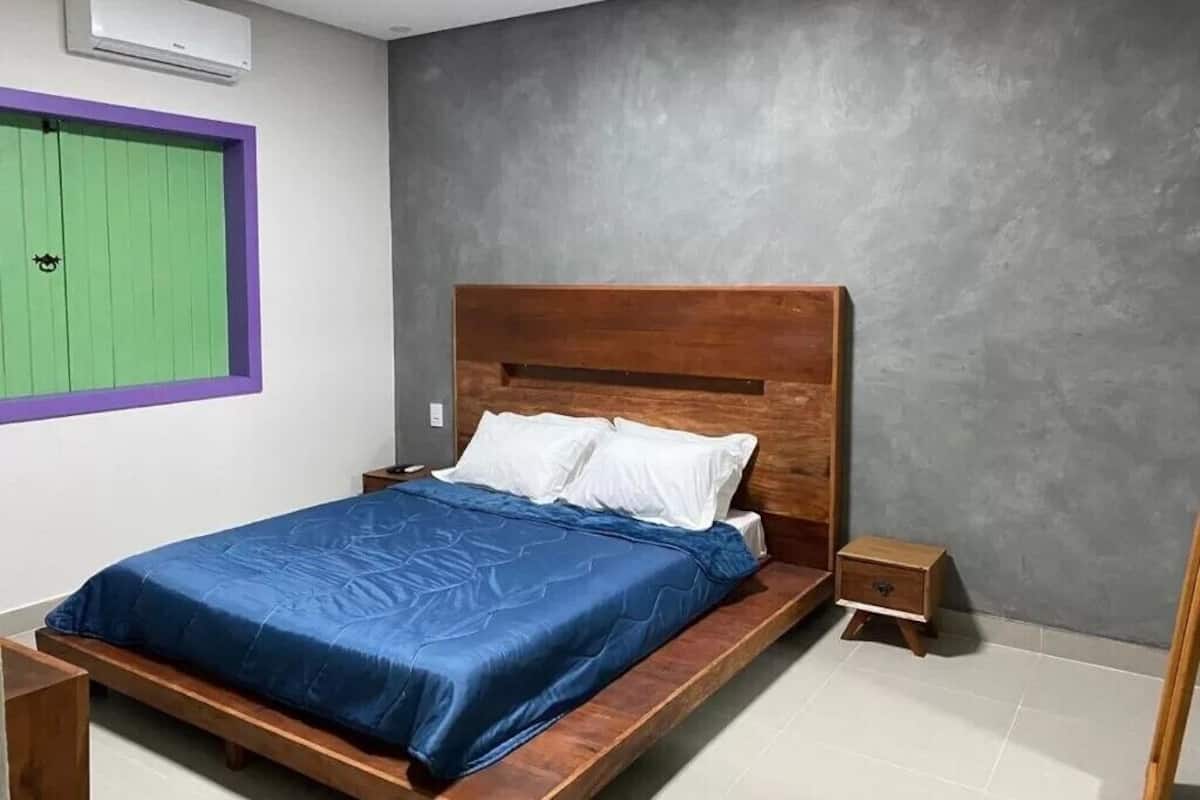 A bedroom with a wooden bed, a nightstand, a green door, and a gray wall.