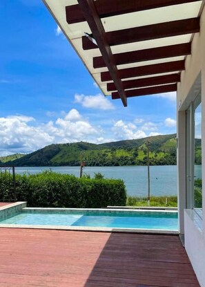 A pool area with a view of a lake and hills. - Pousada Vila do Lago (Capitólio)
