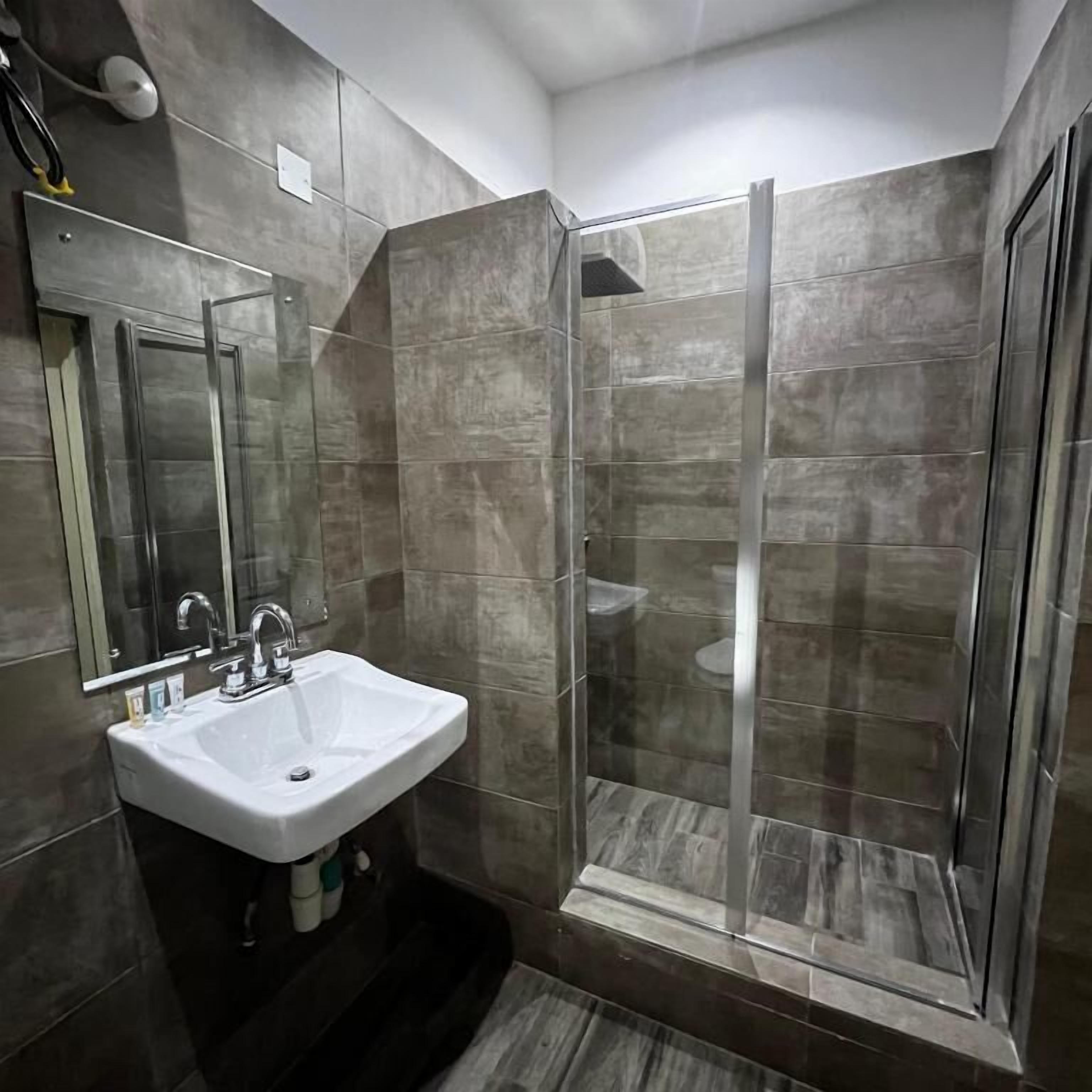 A modern bathroom with a glass-enclosed shower, a white sink, and a mirror.