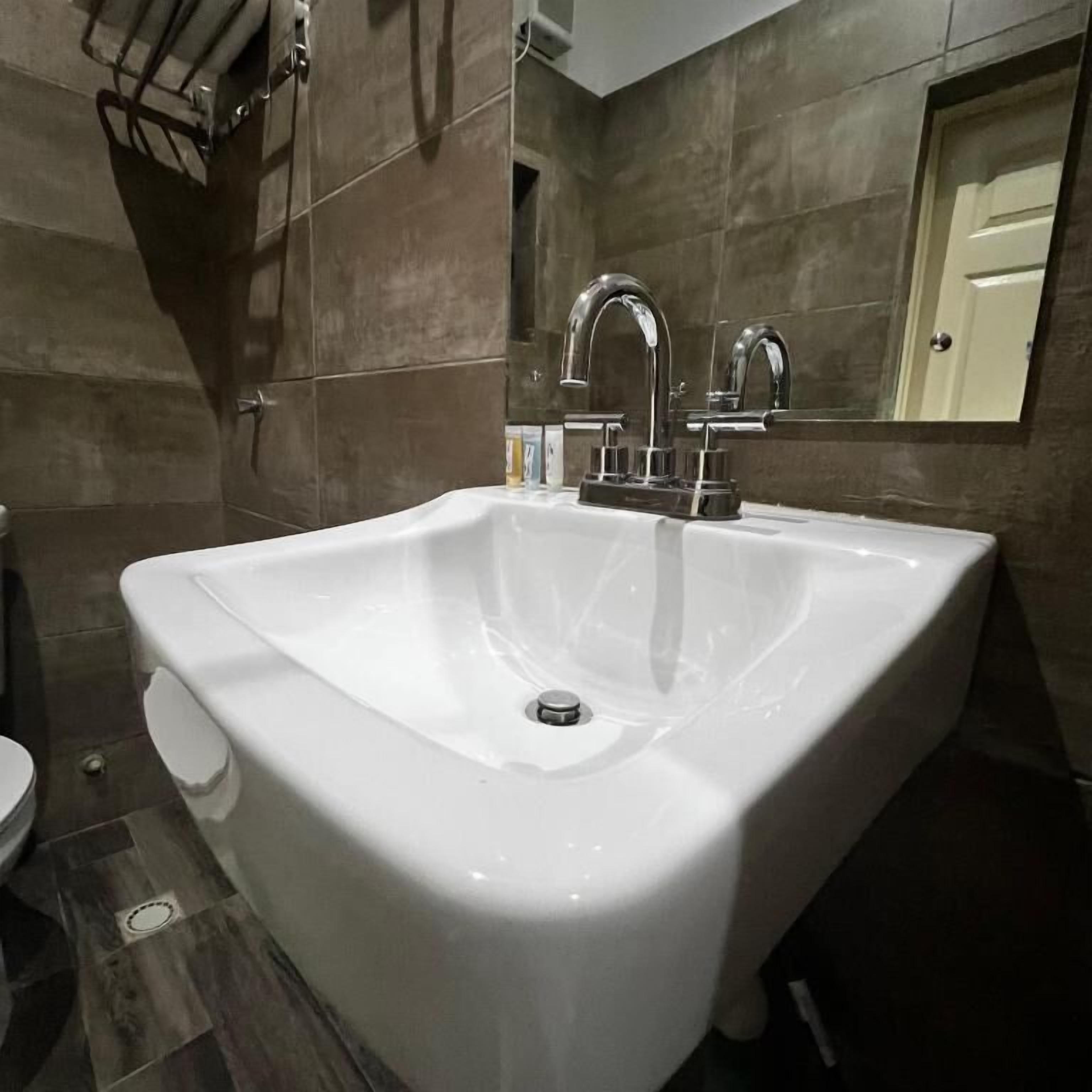 Une salle de bain avec un lavabo blanc, un miroir et des murs carrelés.