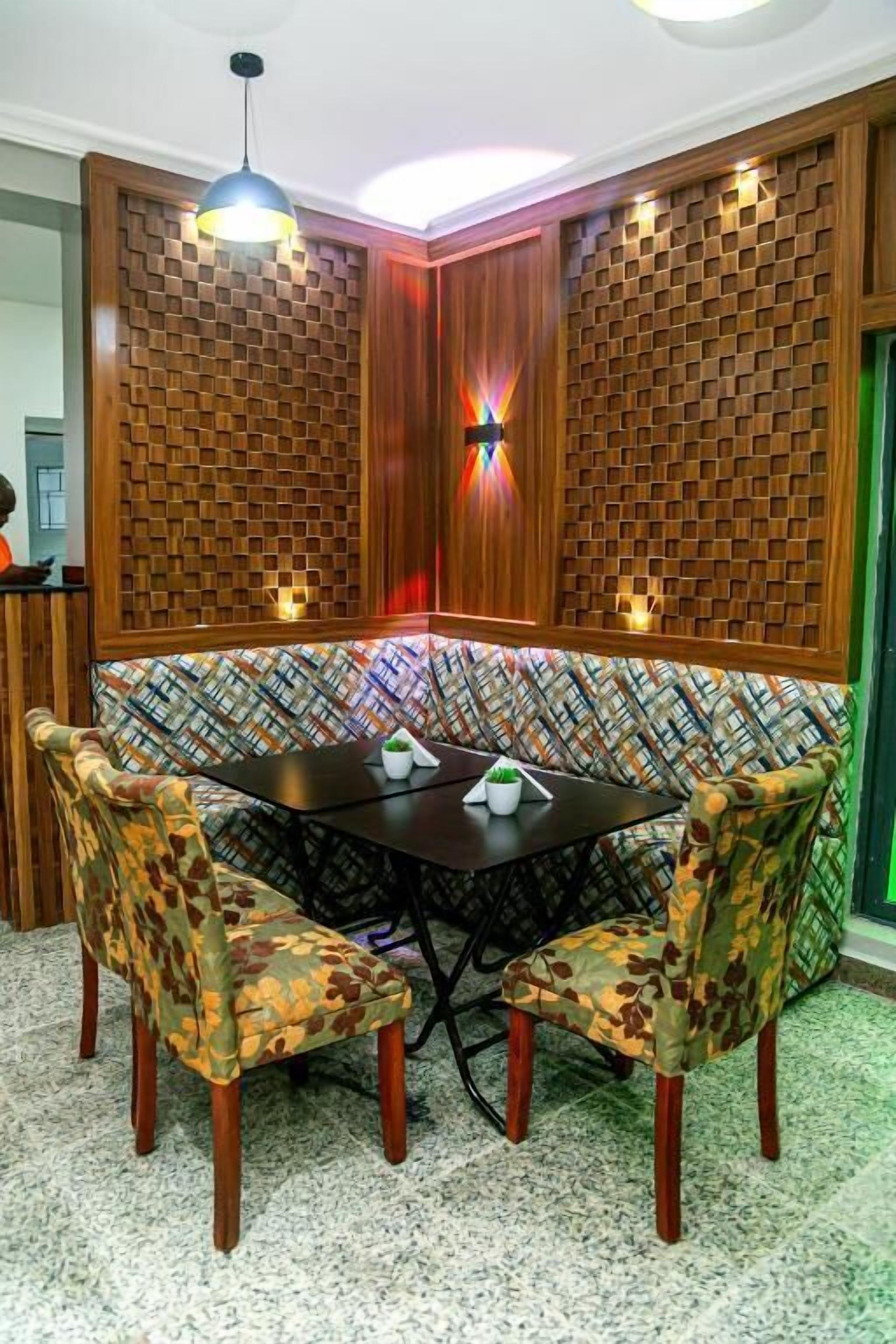A corner seating area with a patterned wall, a round table, and two chairs with floral upholstery.