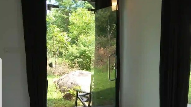 Una stanza con un letto, una porta vetrata che dà su un giardino e lampade a sospensione.