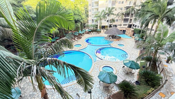 Ein mehrstufiger Poolkomplex mit mehreren Pools, umgeben von Palmen und Sitzbereichen im Freien.