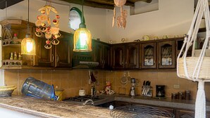 A kitchen with wooden cabinets, a hanging fruit chandelier, and a stove.
