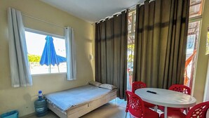 A small room with a bed, a table with chairs, a water dispenser, and a window with curtains. - Flats Praia de Gravatá (São José da Coroa Grande)