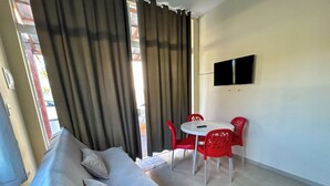 A room with a bed, a table with chairs, a TV on the wall, and a window with curtains. - Flats Praia de Gravatá (São José da Coroa Grande)