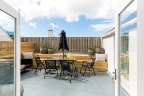 Enclosed roof terrace with outdoor dining table and parasol off The Nest living room, sun trap at The Roost above The White Eagle, Rhoscolyn, Anglesey