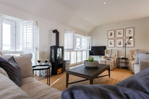 A living room with a sofa, a coffee table, a fireplace, and a TV.