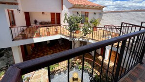 Un bâtiment à deux étages, doté d’un toit recouvert de tuiles, d’un balcon avec une balustrade et de plantes en pot.