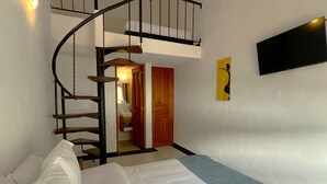 Une chambre à coucher avec un lit, un escalier, un téléviseur à écran plat et une porte en bois.