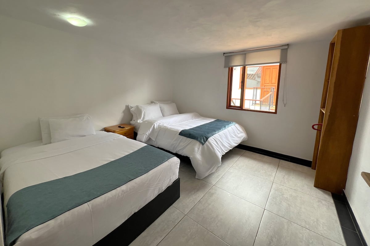 A bedroom with two beds, a window, and a door.