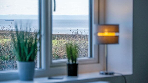 A window with a view of a field and a lamp on the windowsill.