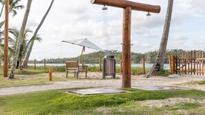 A beach with a wooden swing set, a bench, and a trash bin. - Bangalo Cond Beira Mar c Piscina SH017 (Tamandaré)