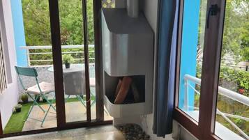 A balcony with a sliding glass door, a small garden area with a stone pathway, and a metal chimney structure.