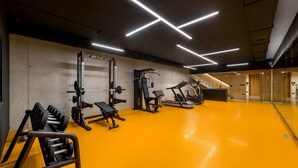 A modern gym with exercise equipment, a bright orange floor, and a staircase leading to an upper level. - Luxury Villa Zio with Pool (Novigrad)